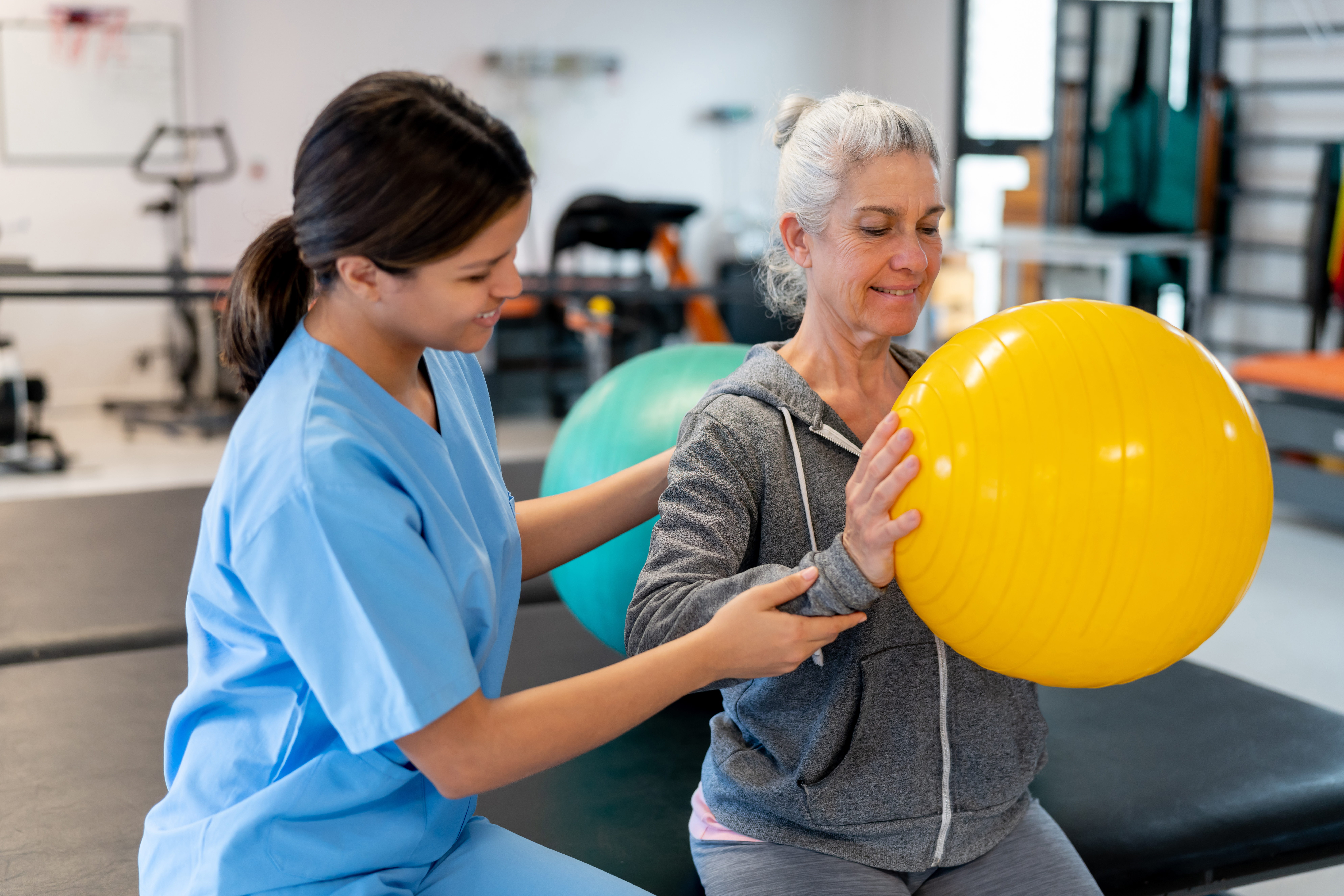 Photo of nurse assisting patient with exercise ball therapy