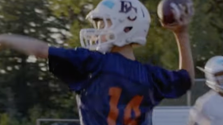 Photo of a boy throwing a football wearing a helmet